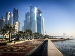 Walking area with some of Qatar's West Bay buildings on the left and on the right the corniche body of water.