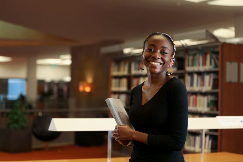 A smiling student holding a book in the GUQ library