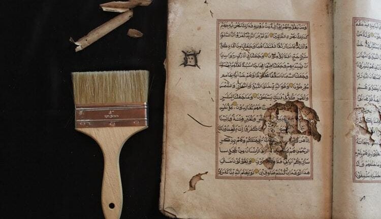 Islamic scripture with a paint brush lying next to it