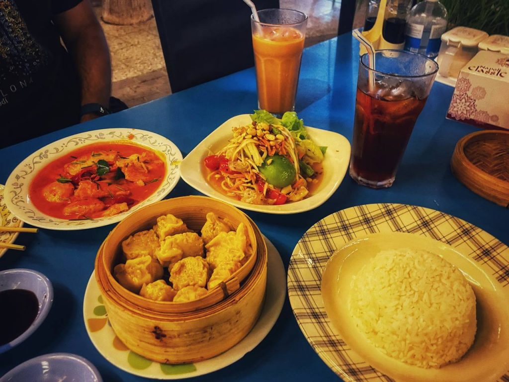 Papaya salad, Panang chicken curry, and chicken xiaomai dumplings with rice are placed on the table