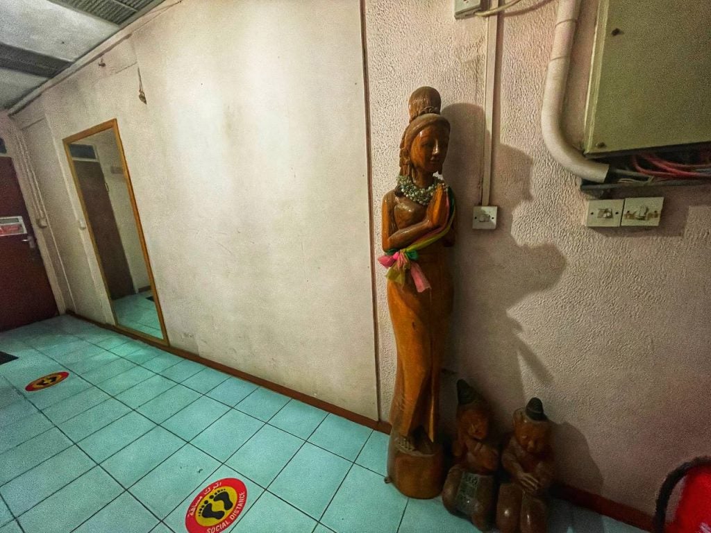 A small wooden Buddha statue welcoming you on the way to the toilet