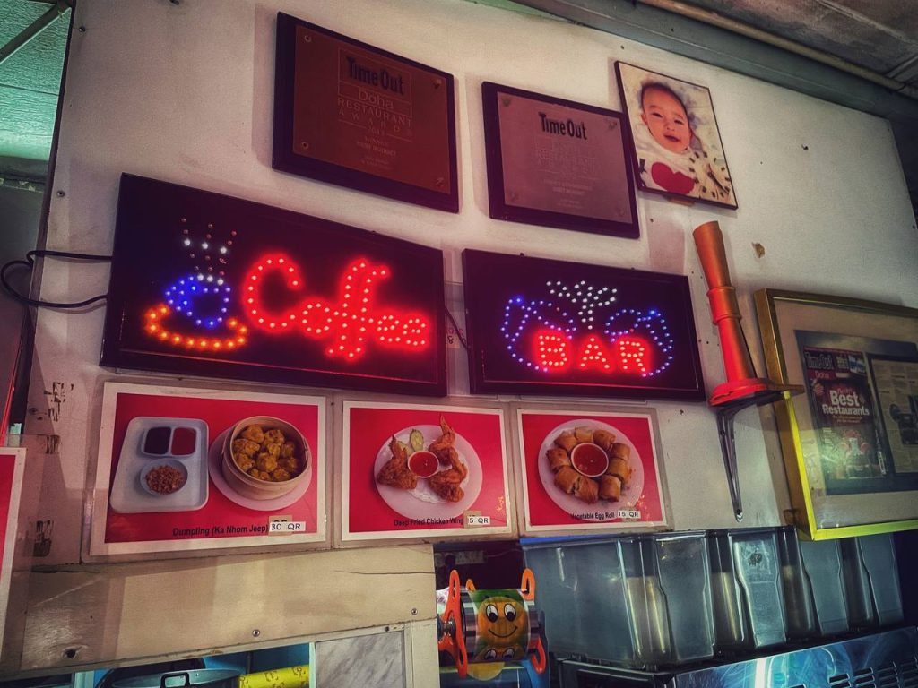 Neon signs of "Coffee" and "Bar" decorating the walls of the restaurant, and the walls feature Thai Snack's rewards