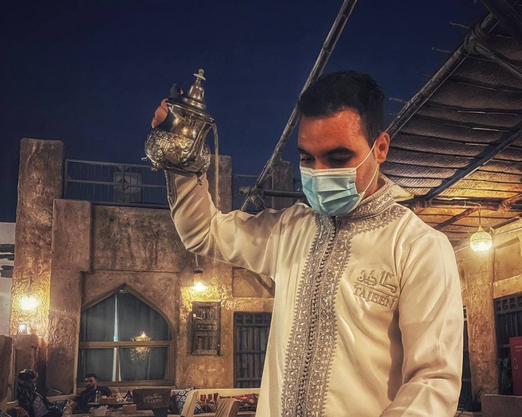 A staff at a Souq Waqif restaurant pouring Moroccan tea