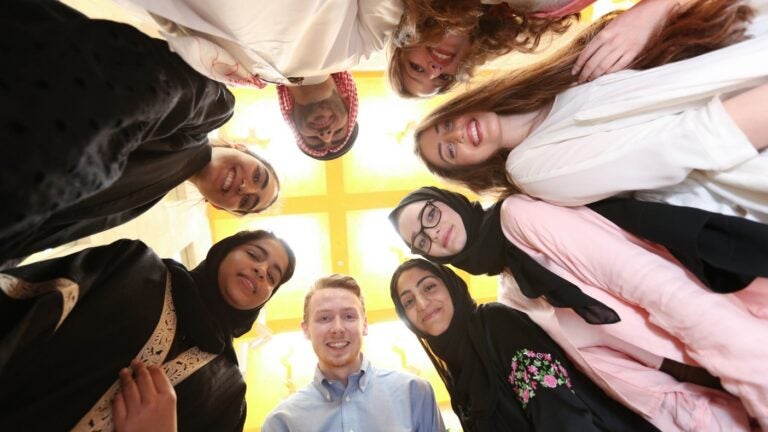 Image of Georgetown students standing in a circle looking down into the camera lense