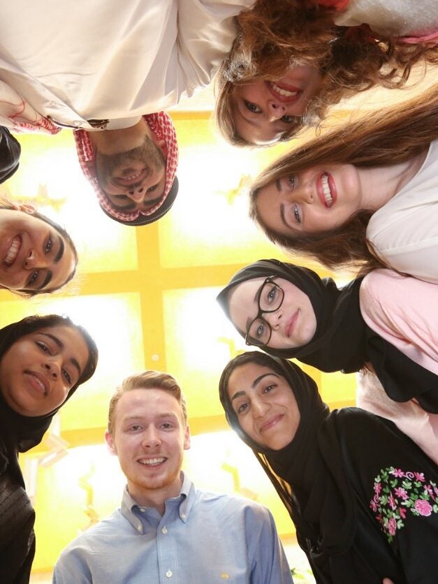 Image of Georgetown students standing in a circle looking down into the camera lense