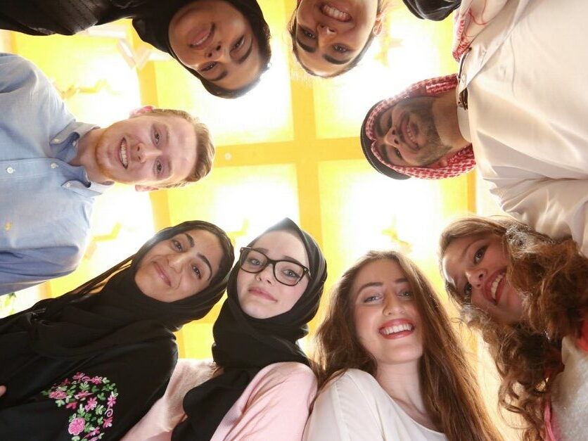 Image of Georgetown students standing in a circle looking down into the camera lense