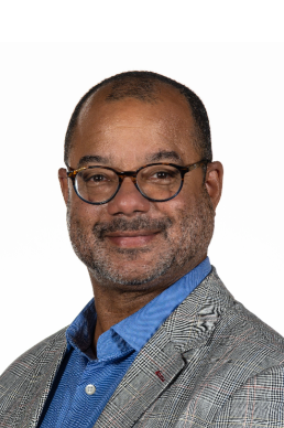 Picture of Marcus King wearing blue shirt and grey jacket. White background