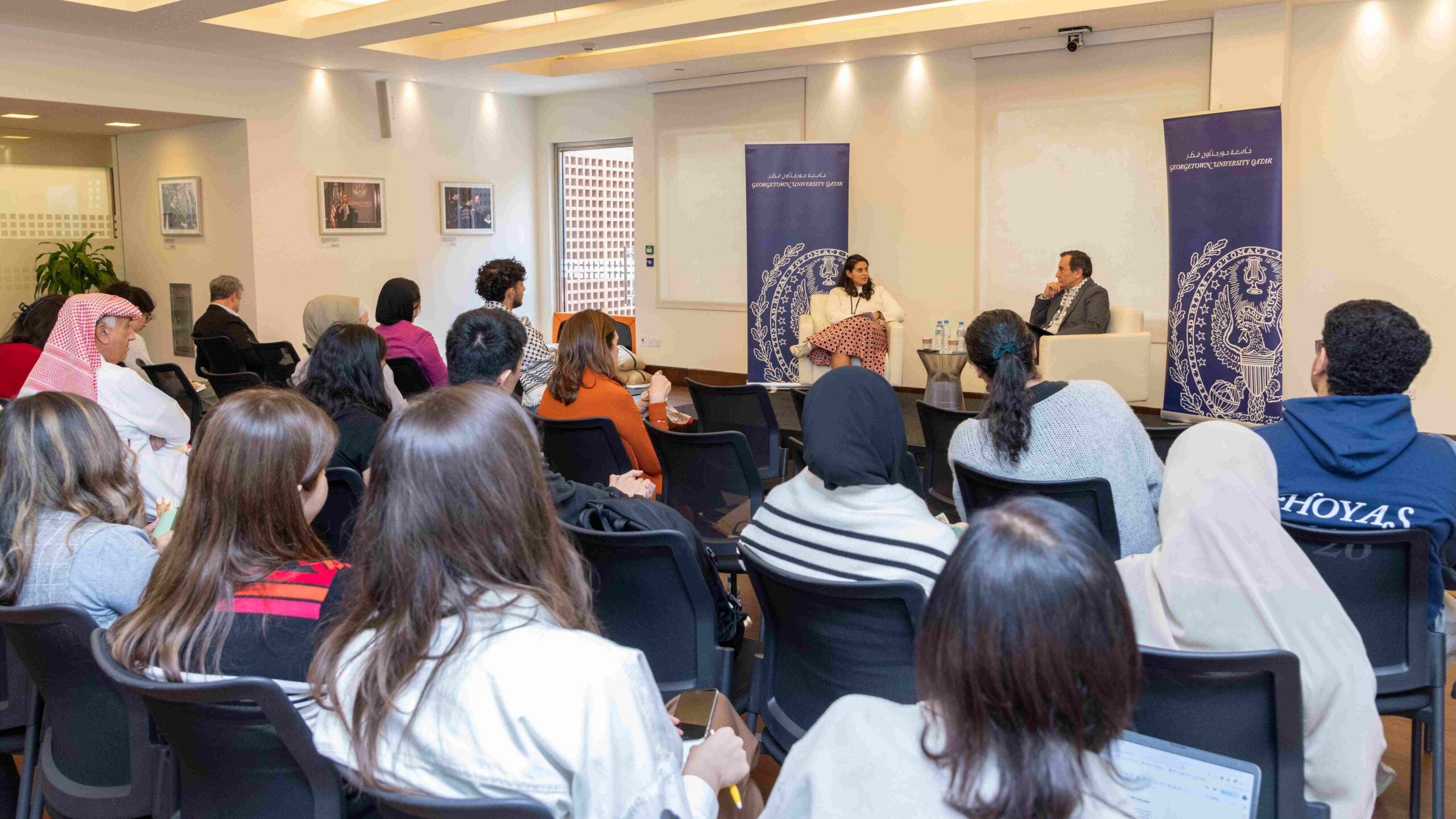 Room full of people with International Lawyer Tamara Essayad talking to Khaled AL-Hroub, Northwestern Qatar